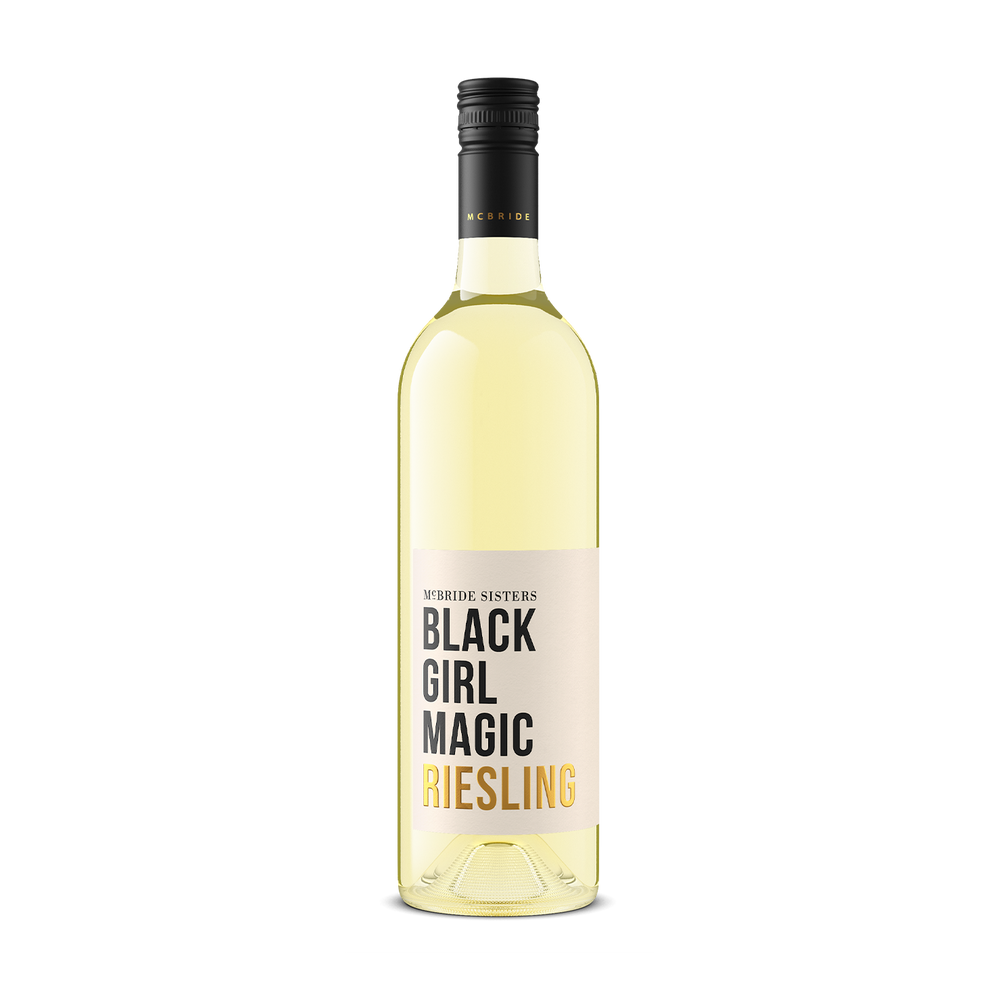 A bottle of white wine with a pale yellow liquid, featuring a cream label with black and gold text that reads McBride SISTERS BLACK GIRL MAGIC RIESLING'. The bottle has a black screw cap and is photographed against a solid white background.