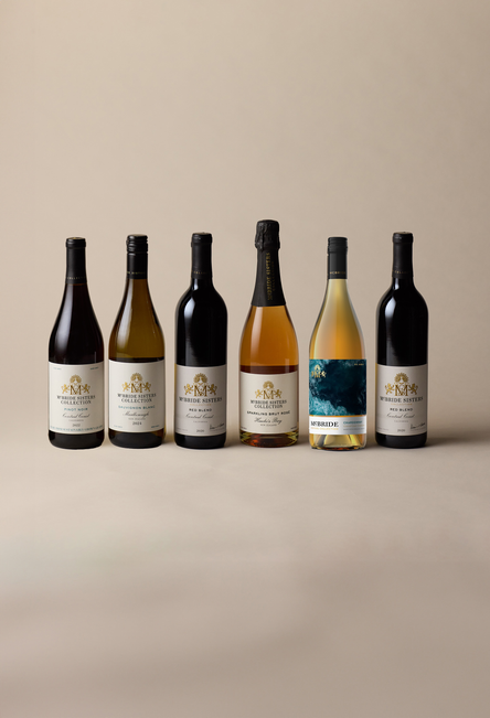 Six bottles of McBride Sisters Collection wine arranged in a row against an off-white background, including red, white, and rosé wine varieties.