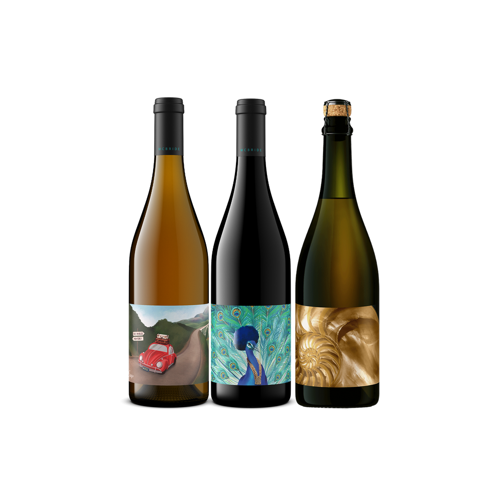 Three wine bottles with colorful illustrated labels, displayed side by side on a plain white background.